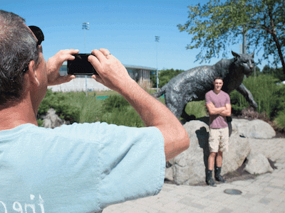 parent taking a picture of their child in front of the wildcat statue